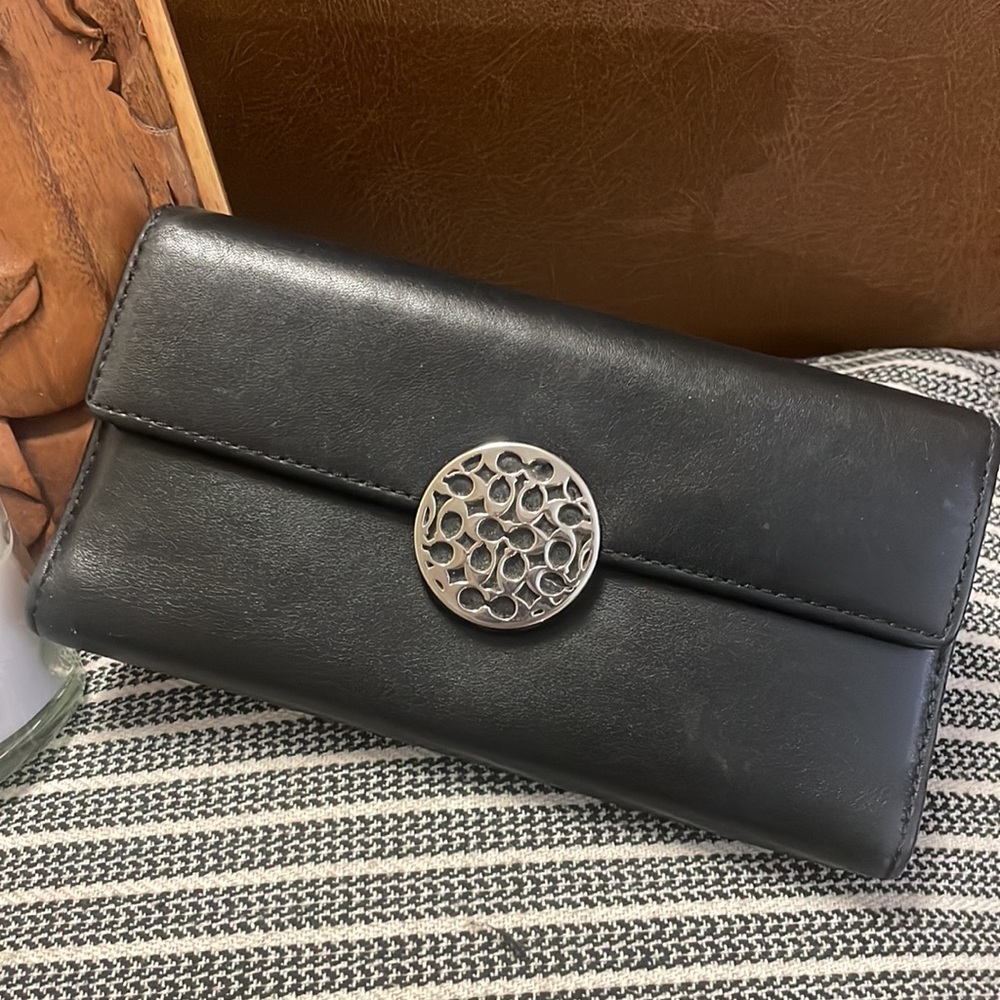 Vintage leather authentic COACH wallet in black. Unique emblem on front.